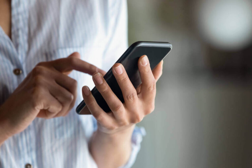 Close up woman holding smartphone in hand, typing on screen stock