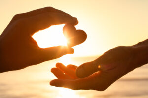 Hand passing heart to another